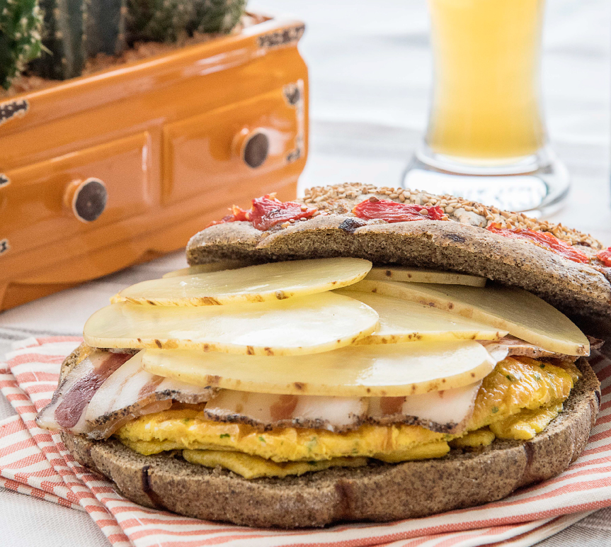 Gluten-free hemp focaccia with cherry tomatoes, stuffed with omelette, bacon and scalded potatoes 