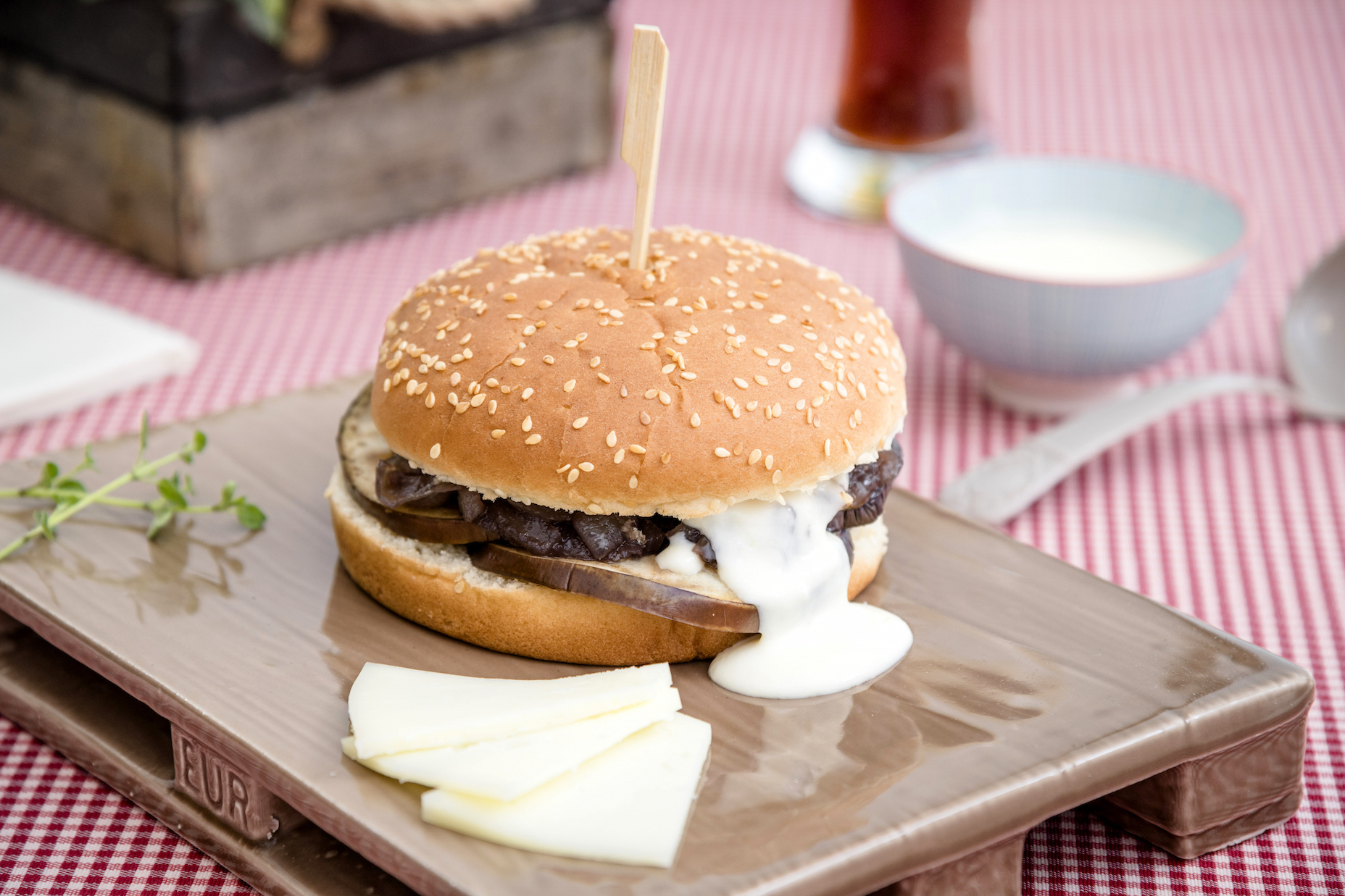 Sándwich de hamburguesas sin gluten con berenjenas a la parrilla y marinadas, crema de pecorino y cebolla caramelizada