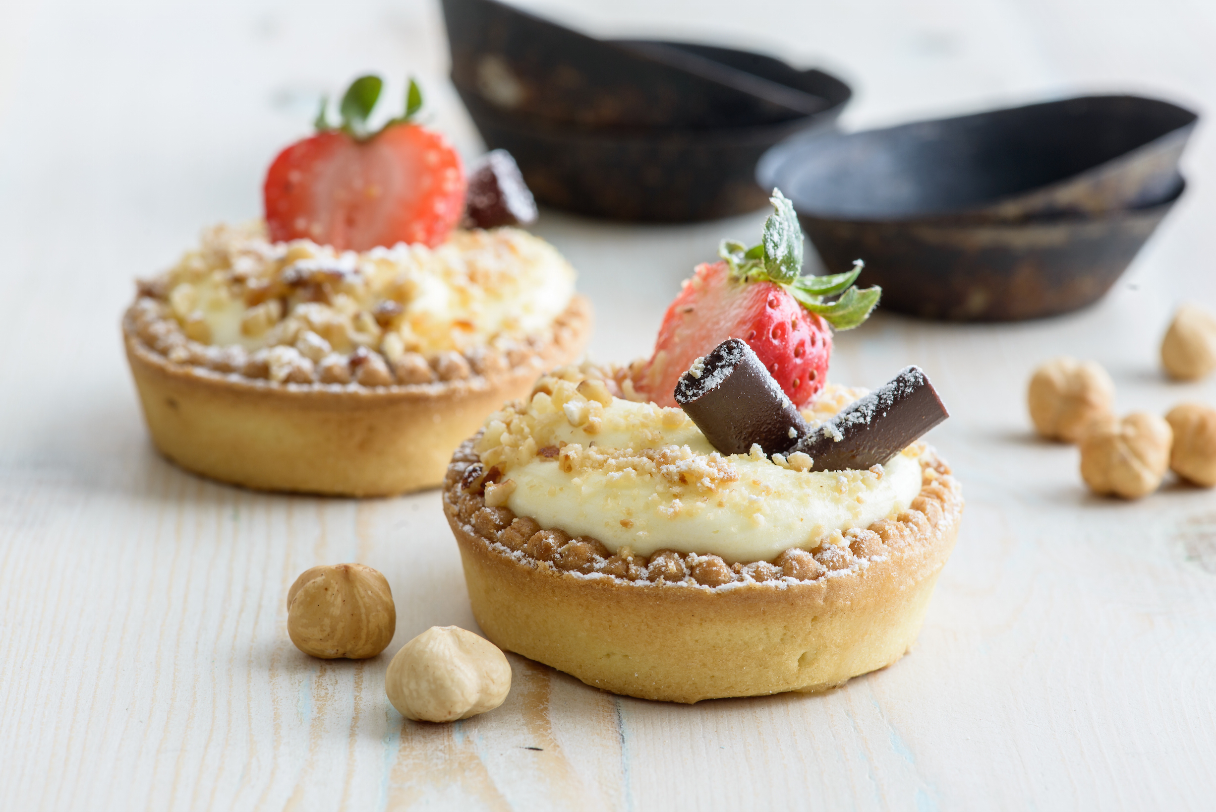 Gluten-free tart with cold cream, chopped hazelnuts, strawberries and chocolate