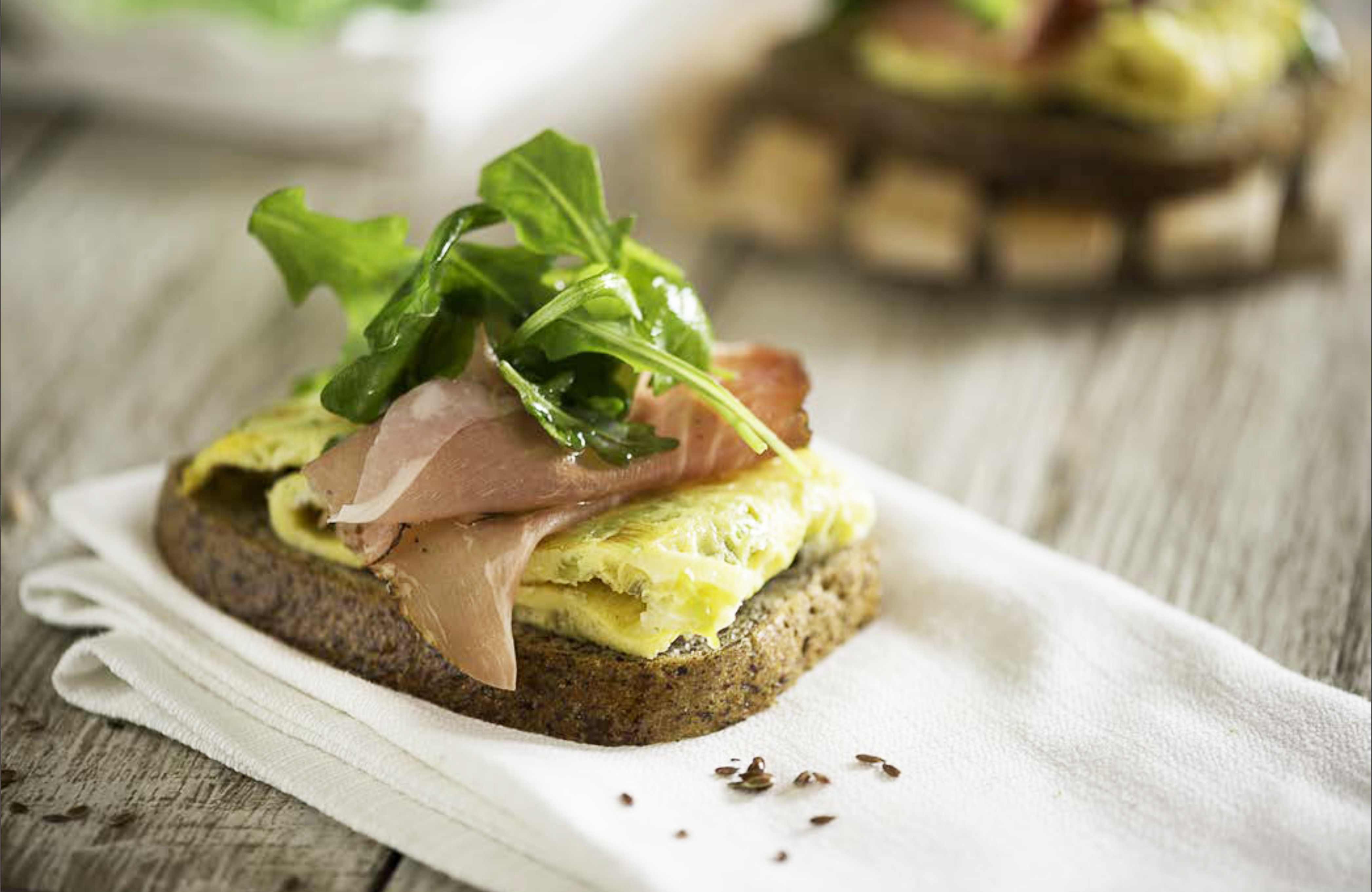 Frittatina di cipollotti freschi con crostone di pane ai semi di lino, speck e rucola