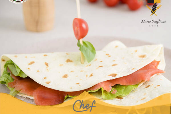 Piadina con salmón ahumado, rodajas de tomate, ensalada crujiente y albahaca